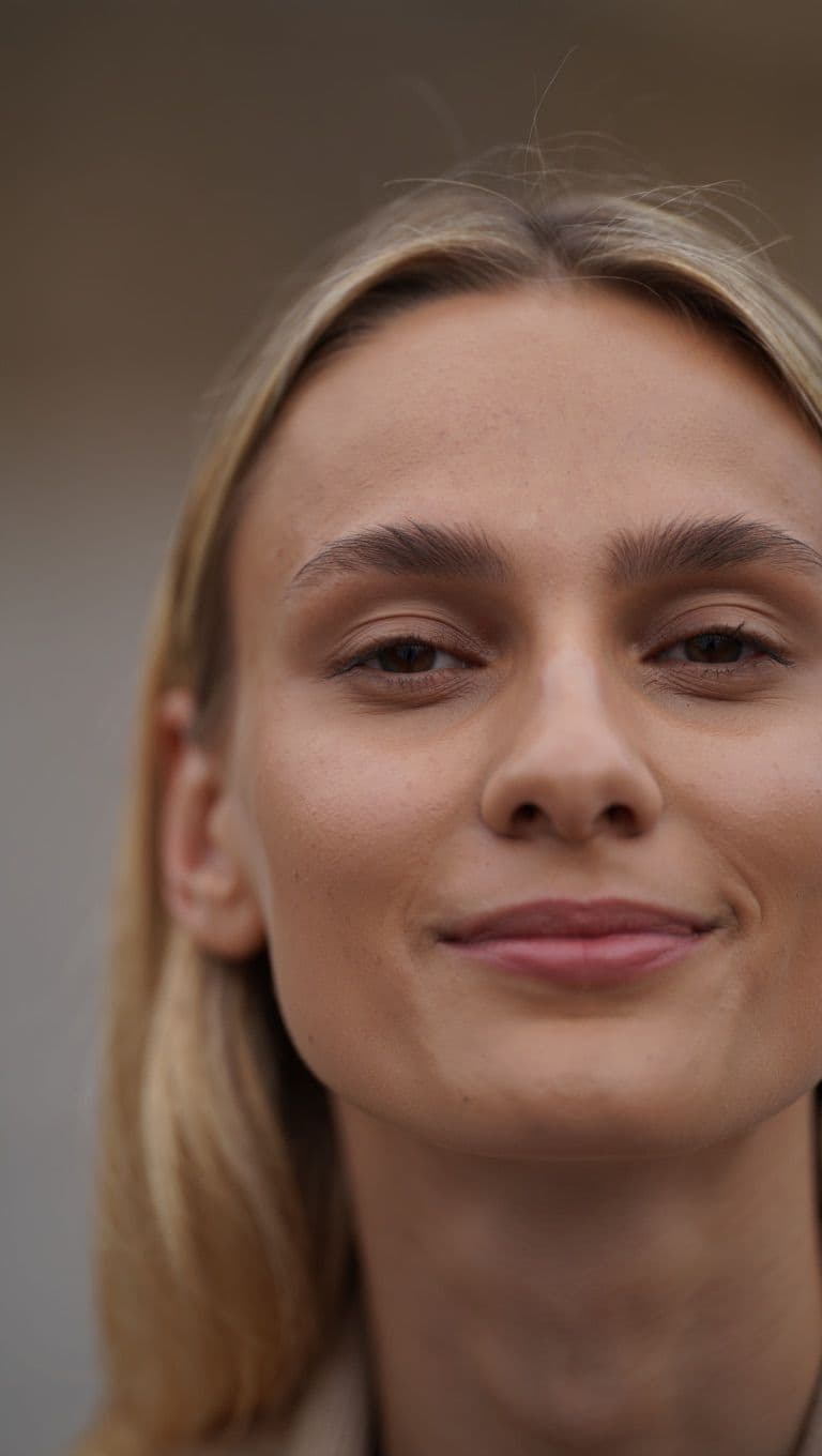 Blonde Frau lächelt sanft, gepflegte Haut, natürliches Make-up